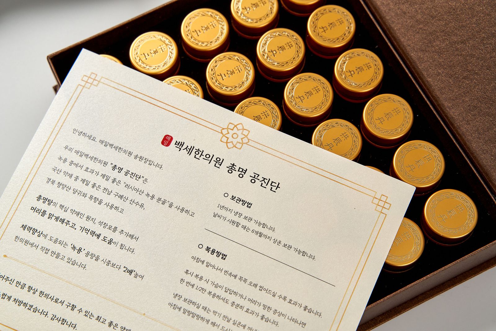 매일백세한의원 총명 공진단 — 원장 안내 카드가 놓인 조제 상자와 금박 환